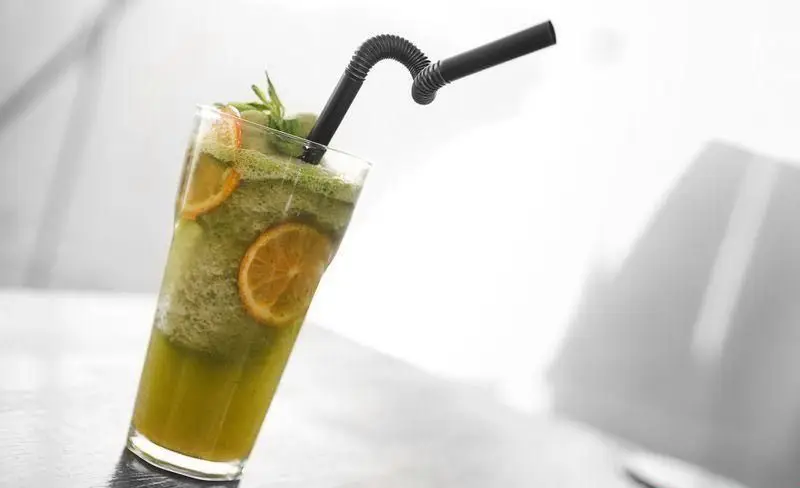 یک لیوان اسموتی سبز رنگ و بسیار خنک با تزئین برش‌های تازه پرتقال و برگ نعنا، ایده‌آل برای روزهای گرم در فست فود چیتر چیکن.
