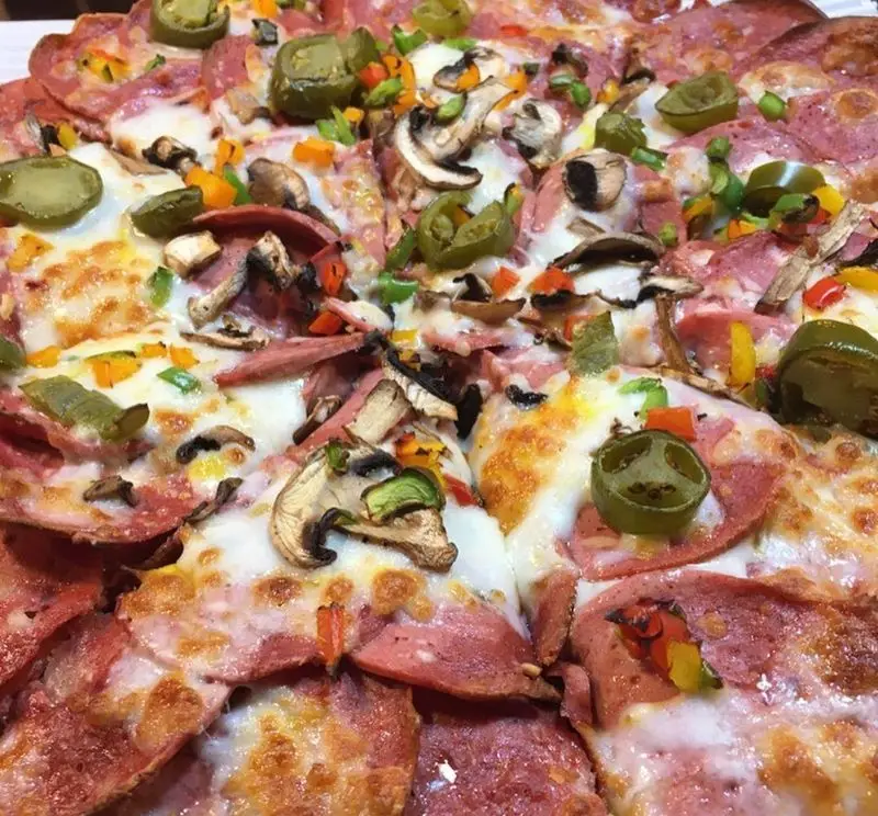 پیتزای پرملات و اشتهاآور کافه رستوران استیج با قارچ تازه، فلفل‌های دلمه‌ای رنگارنگ، فلفل سبز تند و ژامبون ممتاز، آماده سفارش.