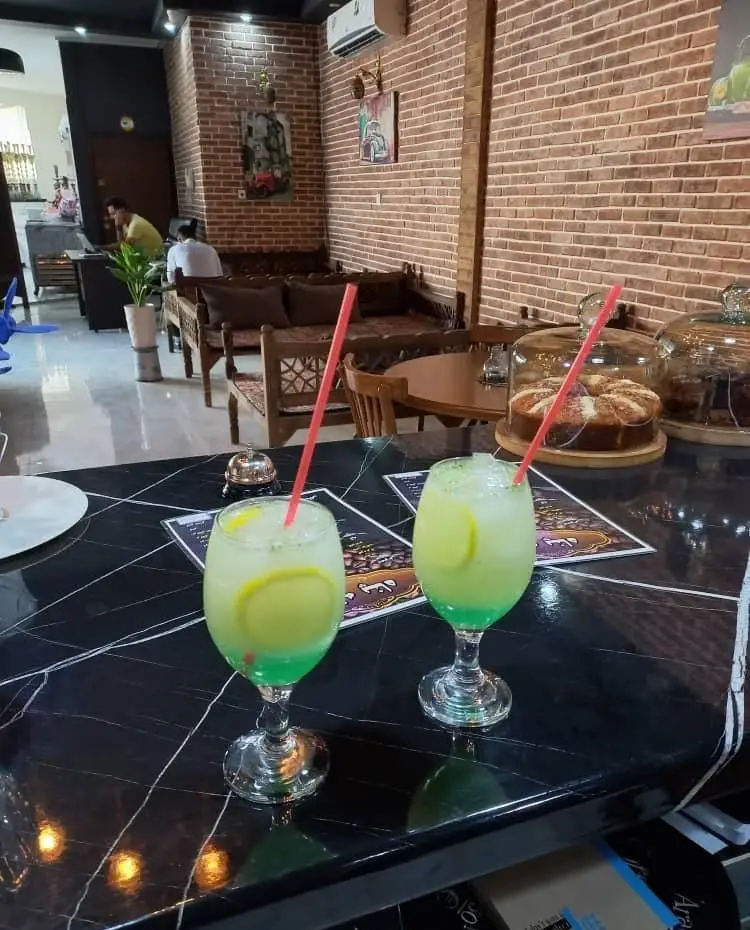 فضای داخلی دنج کافه پناه با میزهای مرمر، نوشیدنی‌های تازه لیمو، دسرهای خوشمزه و طراحی آجری زیبا، محیطی آرام برای شما.