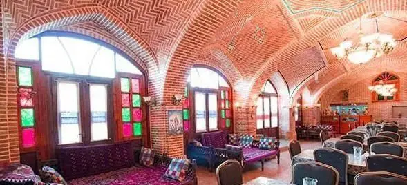 نمای داخلی رستوران سنتی باغ شازده با معماری زیبای آجری، طاق‌های هلالی، پنجره‌های ارسی رنگارنگ و فضایی دلنشین برای صرف غذا.