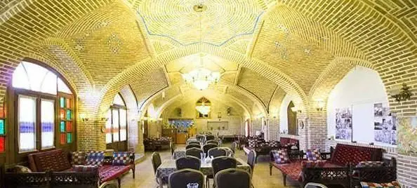 فضای داخلی رستوران سنتی باغ شازده با سقف‌های آجری گنبدی، پنجره‌های رنگی و چیدمان دلنشین، تجربه‌ای اصیل از معماری ایرانی.