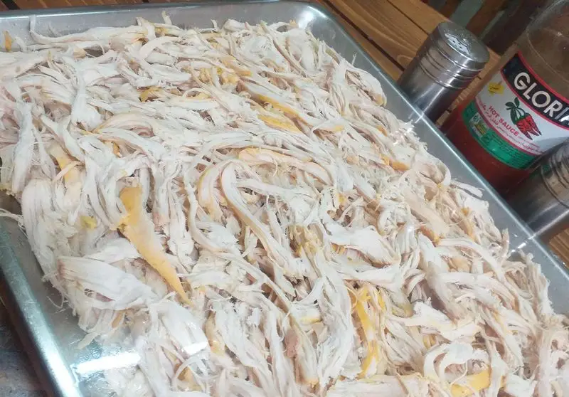 مرغ ریش ریش تازه و پخته در سینی برای تهیه ساندویچ‌های خوشمزه ساندویچ آذر. طعم اصیل با سس تند گلوریا.