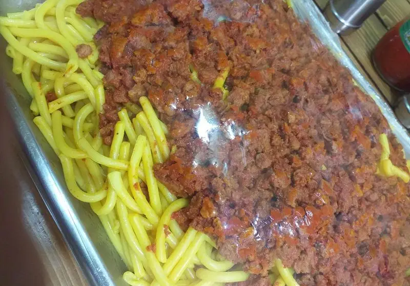 ماکارونی با سس گوشت غلیظ و لذیذ ساندویچ آذر، آماده سرو در سینی، انتخابی عالی برای یک وعده غذای خانگی.