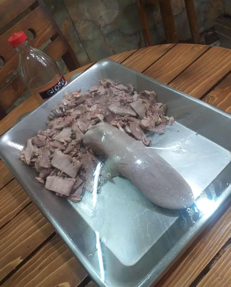 سینی فلزی زبان گوساله پخته شده و خرد شده برای ساندویچ زبان آذر. آماده سازی غذای اصیل و خوش طعم در ساندویچ آذر.