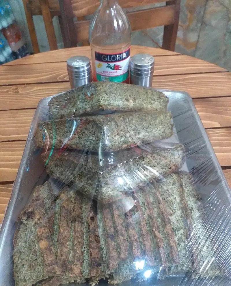 کوکو سبزی‌های برش‌خورده و تازه ساندویچ آذر، آماده برای تهیه ساندویچ با سس تند گلوریا و ادویه‌جات روی میز چوبی.