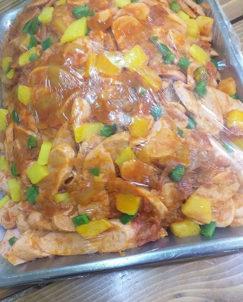 سینی مواد اولیه ساندویچ آذر شامل تکه‌های مرغ، فلفل دلمه‌ای زرد و سبز و سس مخصوص، آماده برای ساندویچ‌های تازه و لذیذ.