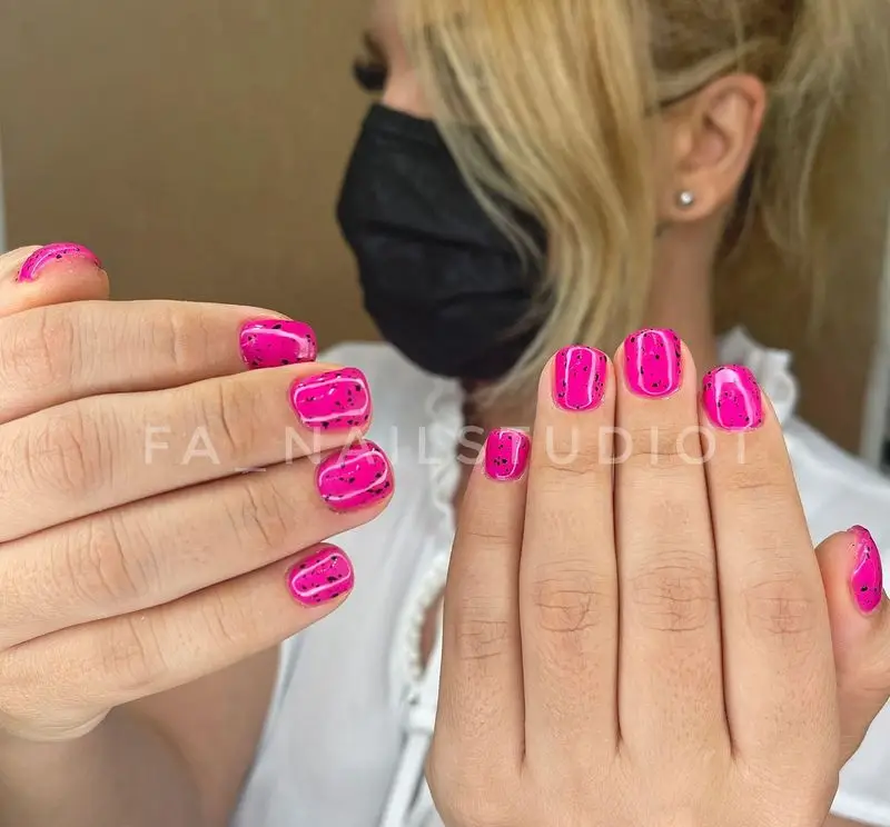 طراحی ناخن فانتزی با لاک صورتی جیغ و طرح تخم بلدرچینی مشکی روی ناخن های کوتاه دخترانه مناسب برای استایل های تابستانی