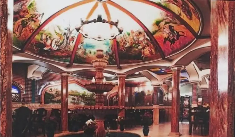 نمای داخلی باشکوه رستوران هفت خوان با سقف گنبدی نقاشی شده، آبنمای سنگی زیبا و ستون‌های تزئینی؛ فضایی سنتی و لوکس.