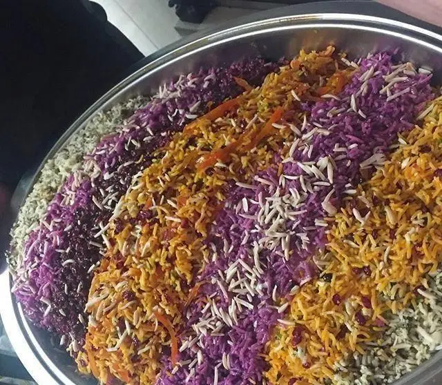 سینی بزرگ پلوهای رنگارنگ و مجلسی رستوران هفت خوان با برنج زعفرانی، پلو بنفش، سبز و سفید، تزئین شده با خلال بادام و زرشک.