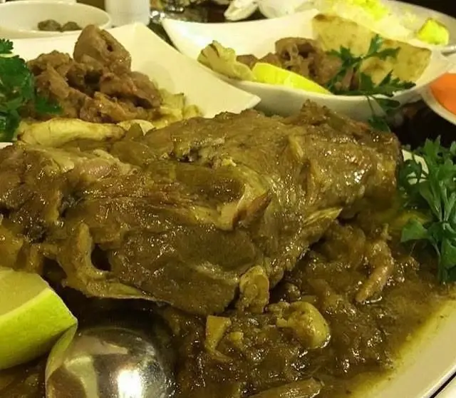 تصویری جذاب از غذای لذیذ رستوران هفت خوان: گوشت گوسفندی یا ماهیچه در سس غلیظ و سبزرنگ به همراه لیمو و سبزی تازه.