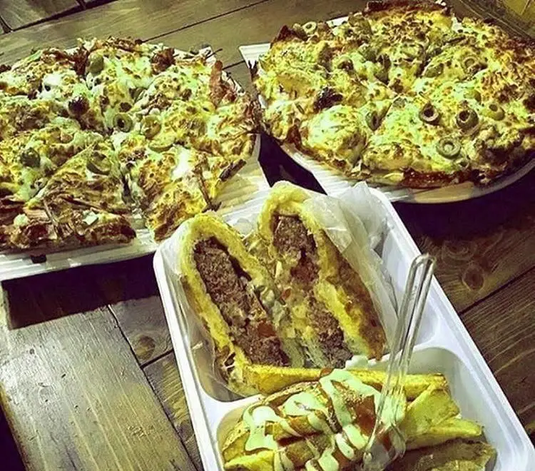 سفره رنگین برگر بن برگر: دو پیتزای بزرگ پر از پنیر و زیتون، برگر ویژه دو نیم شده و سیب‌زمینی سرخ‌کرده با سس، فست فود لذیذ.