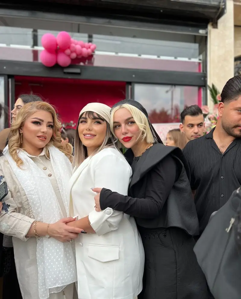 سه زن جوان با استایلهای شیک مجلسی سفید و مشکی در حال در آغوش گرفتن یکدیگر در مراسم افتتاحیه سالن زیبایی و آرایشگاه زنانه