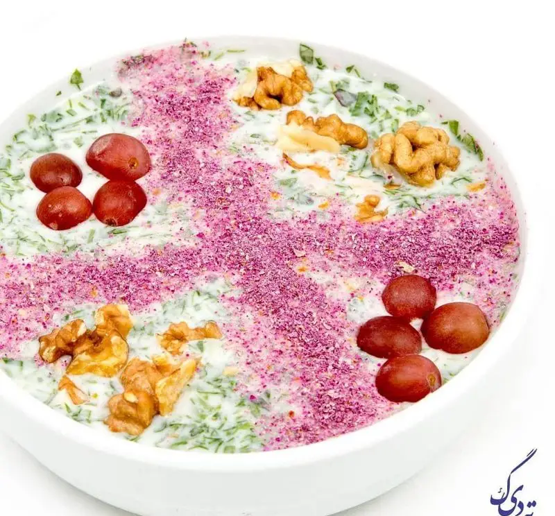 ماست و خیار مجلسی رستوران ته دیگ. این پیش غذای خوشمزه و تازه ایرانی با تزیین گردو، انگور قرمز و پودر گل محمدی زینت داده شده است.