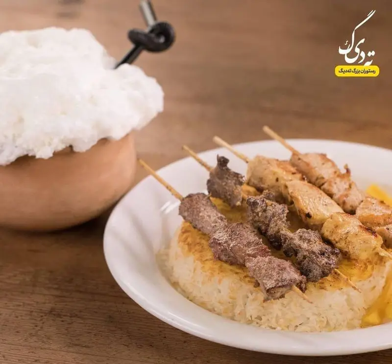 سفره‌ای شاهانه از کباب گوشت و جوجه کباب روی برنج ته دیگ زعفرانی همراه با دوغ خنک در رستوران ته دیگ.