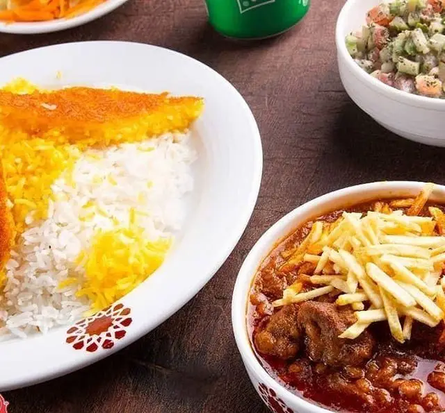 غذای سنتی ایرانی شامل برنج زعفرانی با ته دیگ طلایی، خورش قیمه با سیب زمینی سرخ کرده و سالاد تازه از تهیه غذا و فست فود به پخت.