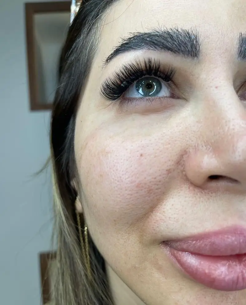 تصویر نزدیک از اکستنشن مژه والیوم مشکی، بلند و پرپشت روی چشم رنگی زنانه به همراه ابروهای مرتب و لیفت شده طبیعی