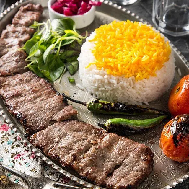 چلوکباب برگ لذیذ رستوران عیار شمرون با برنج زعفرانی اعلا، فلفل و گوجه کبابی، در کنار سبزی و ترشی تازه.