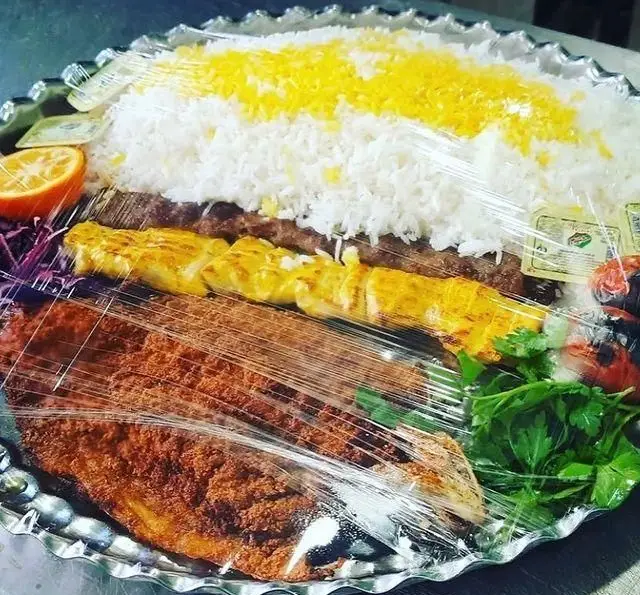 کافه تاریک: سینی غذای ایرانی شامل چلوکباب، جوجه کباب، ماهی سرخ شده، برنج زعفرانی و مخلفات تازه. سفارش آنلاین غذای لذیذ