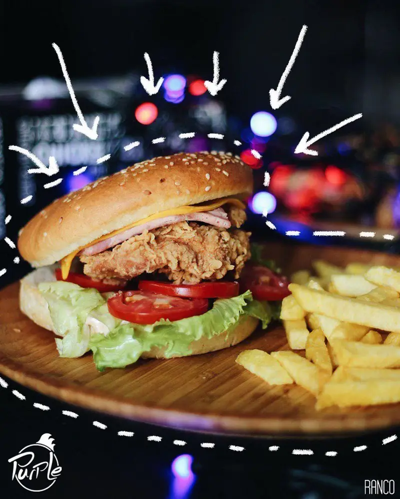 همبرگر مرغ سوخاری کریسپی پرپل به همراه سیب‌زمینی سرخ‌شده طلایی و تازه، سرو شده بر روی تخته چوبی، انتخابی دلپذیر از منوی پرپل سوخاری.