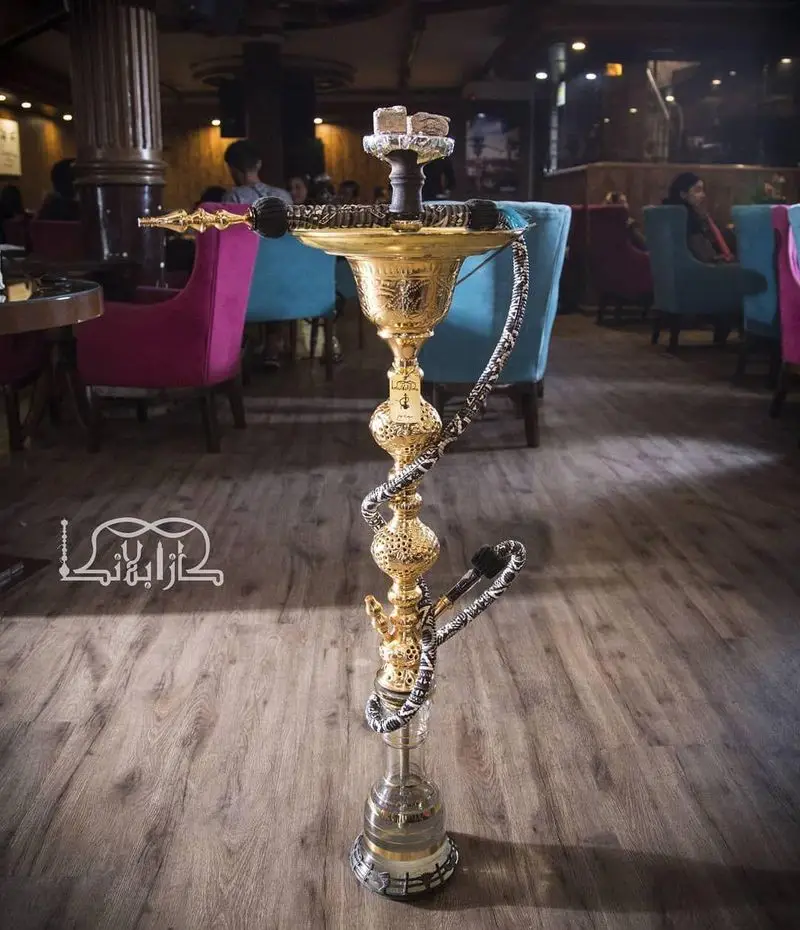 قلیان طلایی و مجلل در کافه عربی کازابلانکا، نمایشگر فضای داخلی شیک و دنج با صندلی‌های رنگی و دکوراسیون سنتی و مدرن.