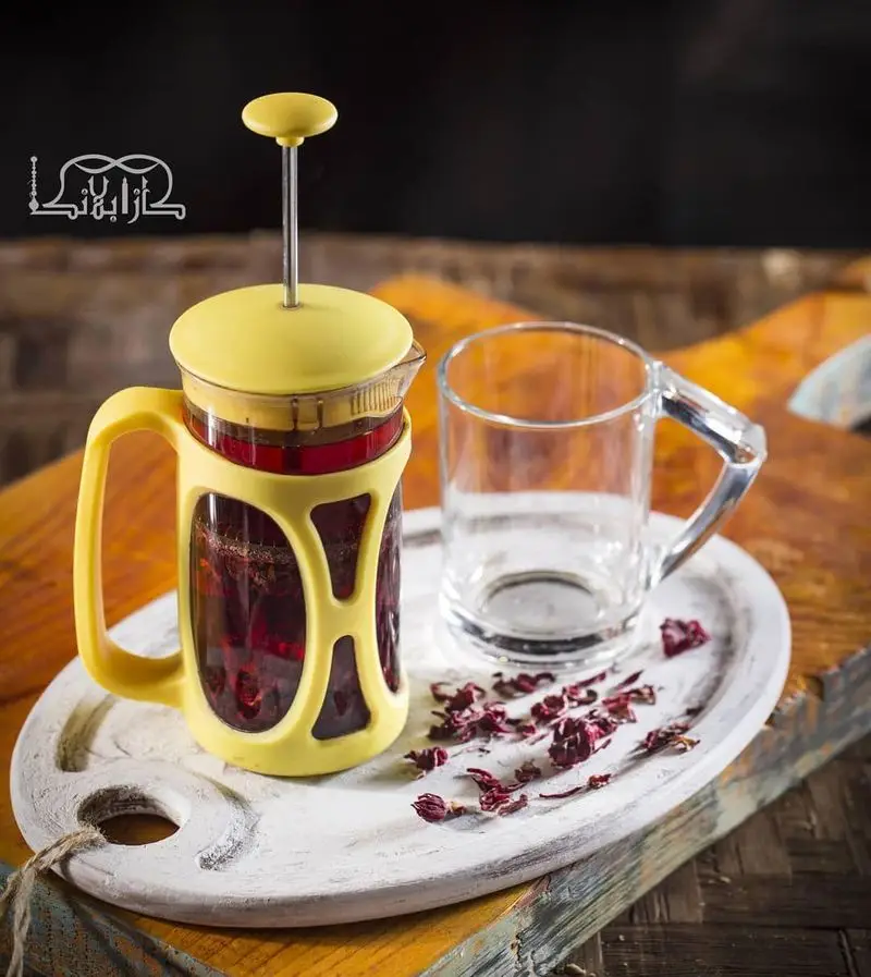 فرنچ پرس زرد حاوی چای ترش داغ و فنجان شیشه‌ای، سروی آرامش‌بخش و دلنشین از کافه عربی کازابلانکا.