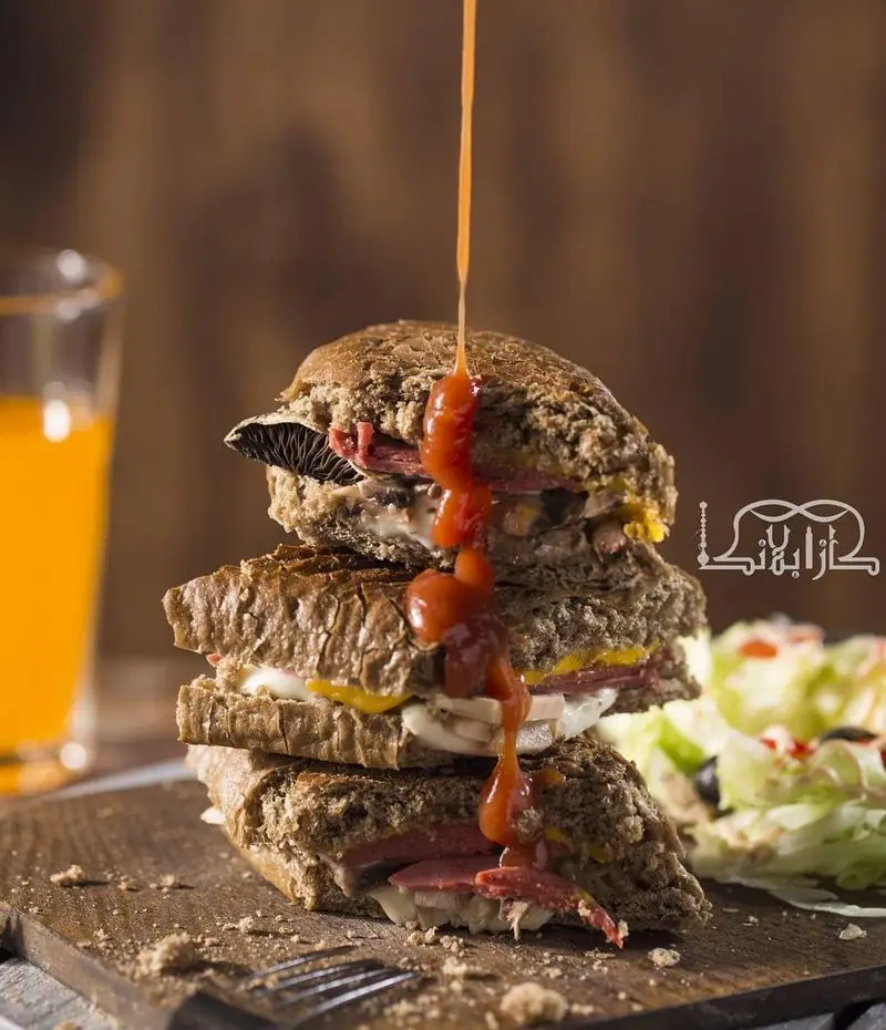 ساندویچ‌های پنینی چندلایه خوشمزه کافه عربی کازابلانکا با سس، گوشت، قارچ و پنیر، همراه نوشیدنی و سالاد برای ناهار.