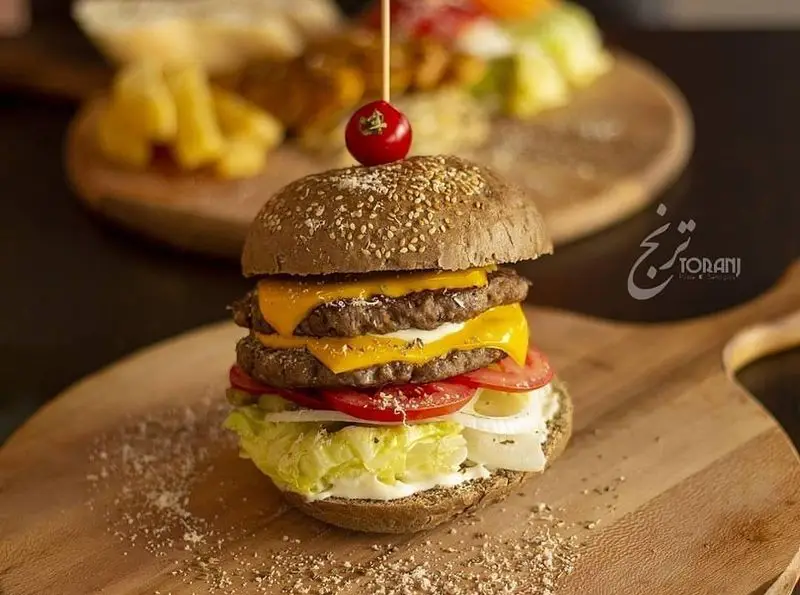 تصویر همبرگر دوبل چیز اشتهاآور ترنج با نان سبوس‌دار، کاهو، گوجه، پیاز و سس، آماده سرو در فست فود ترنج شعبه ۳.