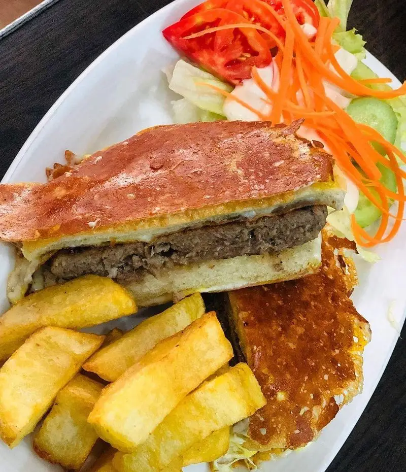 غذای خوشمزه فست فود ترنج شعبه ۳: ساندویچ گریل شده گوشت با نان ترد، همراه سیب زمینی سرخ کرده و سالاد فصل تازه و رنگارنگ.