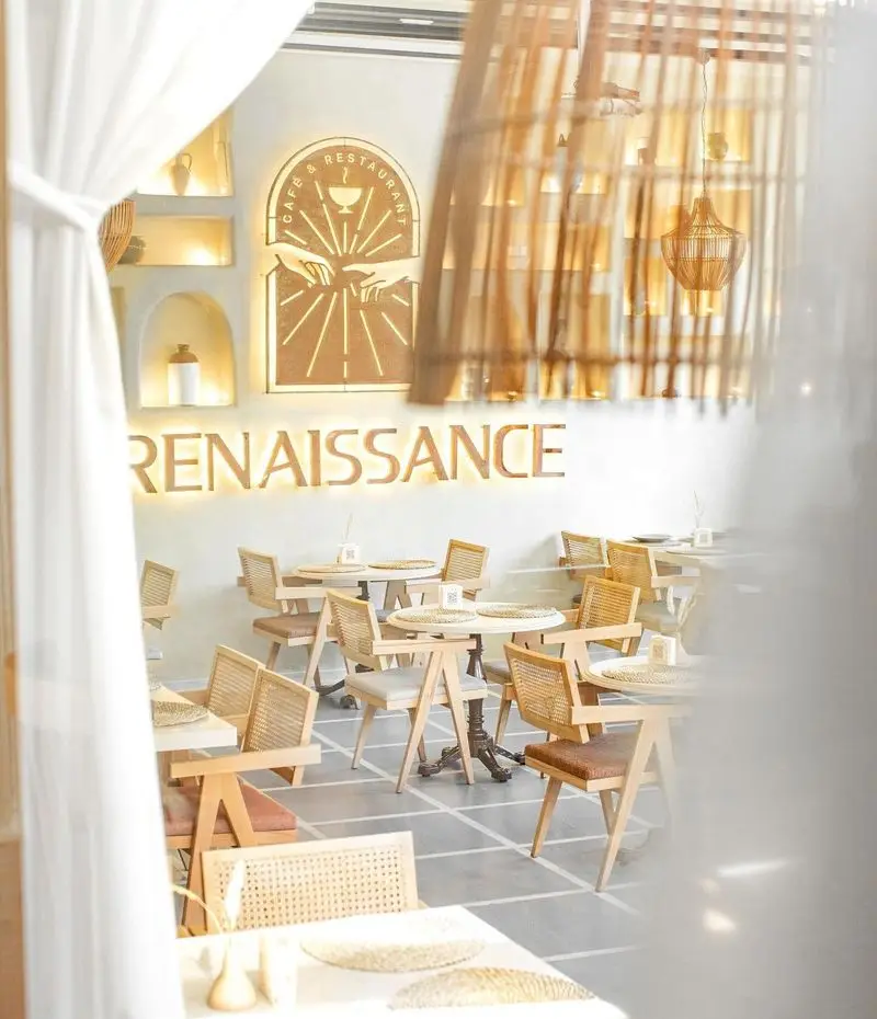 نمایی از دکوراسیون داخلی کافه رستوران رنسانس، با میز و صندلی‌های چوبی و حصیری مدرن و فضایی دنج و شیک برای مشتریان.