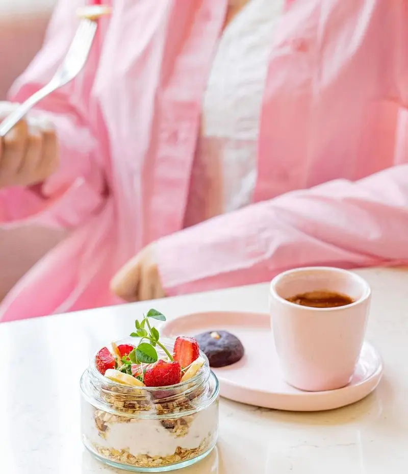 تصویری از میز صبحانه دلچسب در کافه رستوران رنسانس: گرانولای میوه‌ای، قهوه تازه و شیرینی، آماده برای شروع روزی پرانرژی.