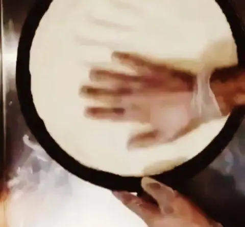 تصویری از آماده‌سازی و پهن کردن خمیر پیتزای تازه با دست، برای پخت پیتزای خوشمزه در آشپزخانه پیتزا و کباب ترکی علی بابا، تضمین کیفیت و طعم بی‌نظیر.