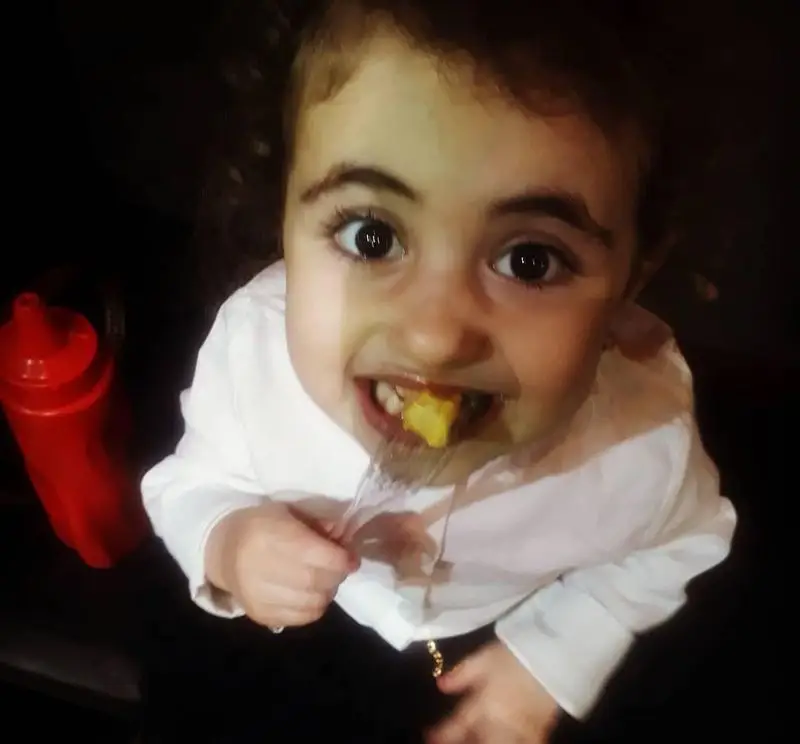 کودکی خندان در پیتزا و کباب ترکی علی بابا مشغول لذت بردن از سیب زمینی سرخ کرده، نشان‌دهنده محیط دلنشین و غذاهای عالی رستوران ما.