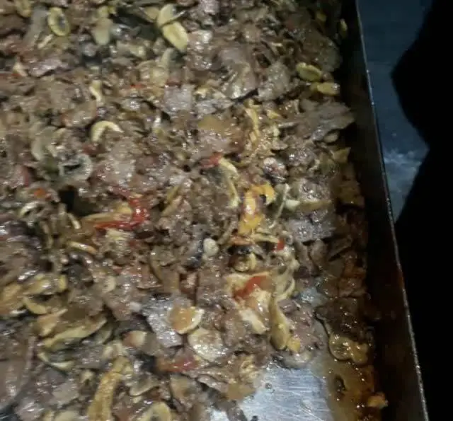 تصویری از سینی حاوی گوشت دونر کباب ترکی تازه پخته شده با ادویه‌جات و سبزیجات معطر در آشپزخانه علی بابا. آماده برای پیتزا و کباب ترکی.