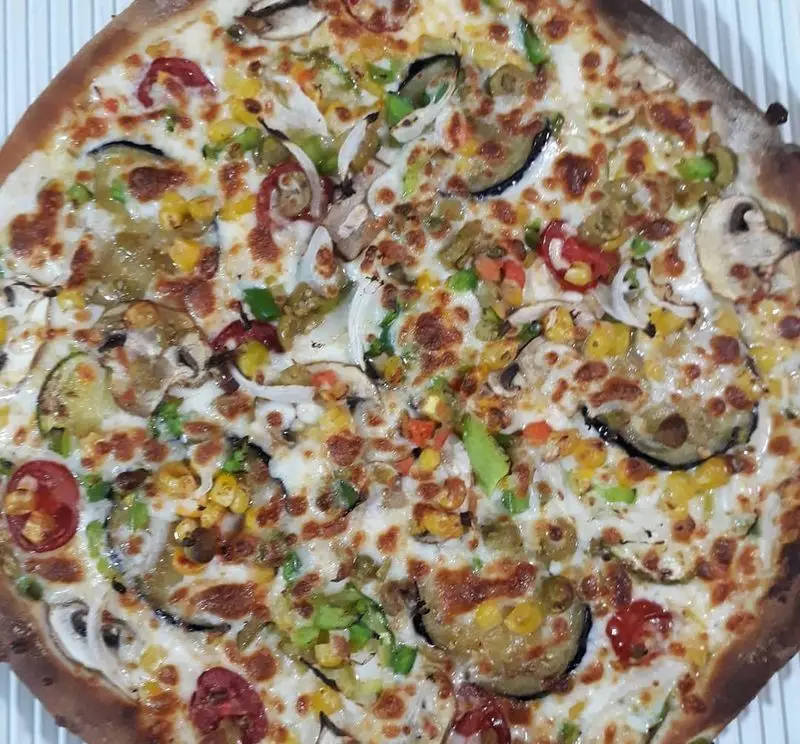 پیتزای سبزیجات تازه و دلپذیر پیتزا و کباب ترکی علی بابا، شامل قارچ، بادمجان، ذرت، فلفل دلمه‌ای و زیتون، آماده سرو.