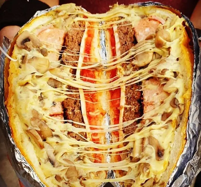 ساندویچ بزرگ و خوشمزه از پیتزا و کباب ترکی علی بابا، پر از گوشت، سوسیس، قارچ و پنیر کشدار ذوب شده.