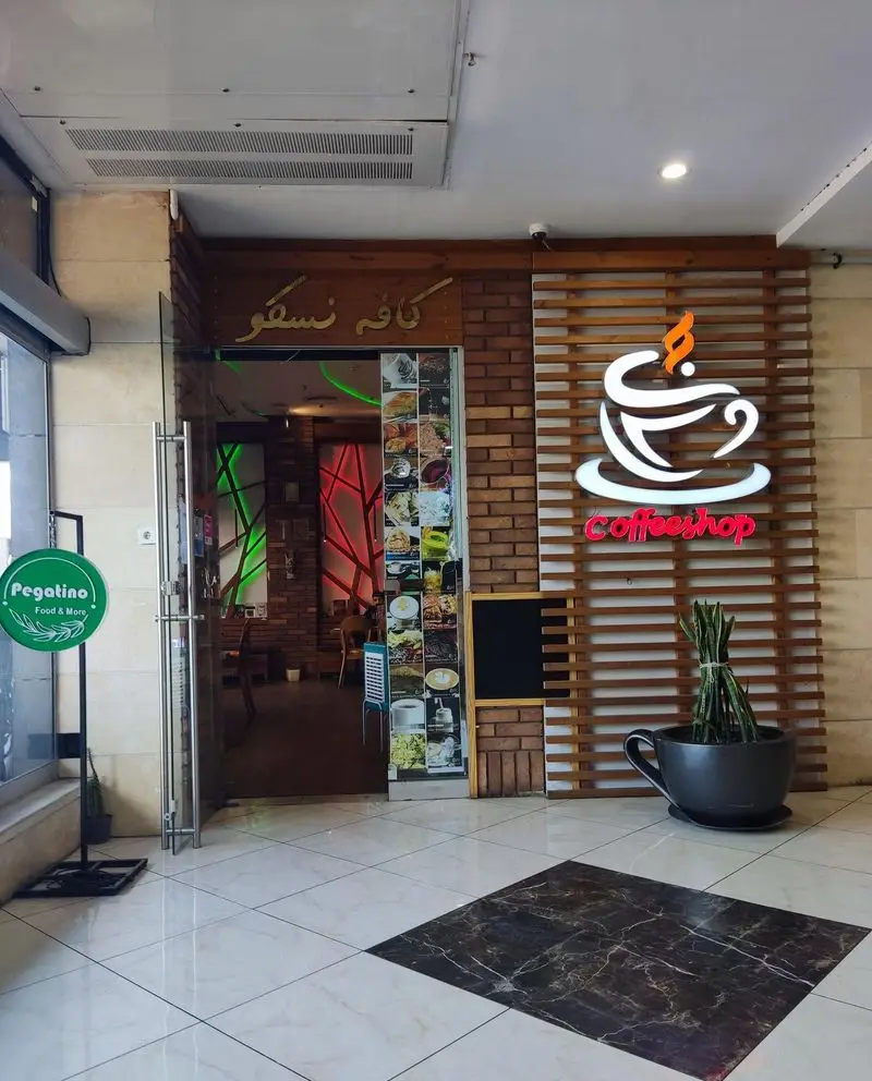 تصویر ورودی کافه رستوران نسکو، شامل تابلوی کافه نسکو و لوگوی کافی شاپ نورانی. دکوراسیون داخلی و خارجی مدرن و منوی غذا.