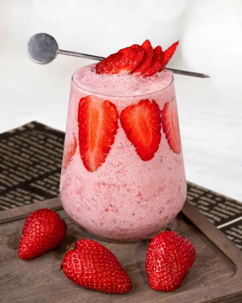 اسموتی توت فرنگی تازه و دلپذیر با برش‌های میوه و توت فرنگی‌های کامل، انتخابی عالی از کافه رستوران لاماسو.