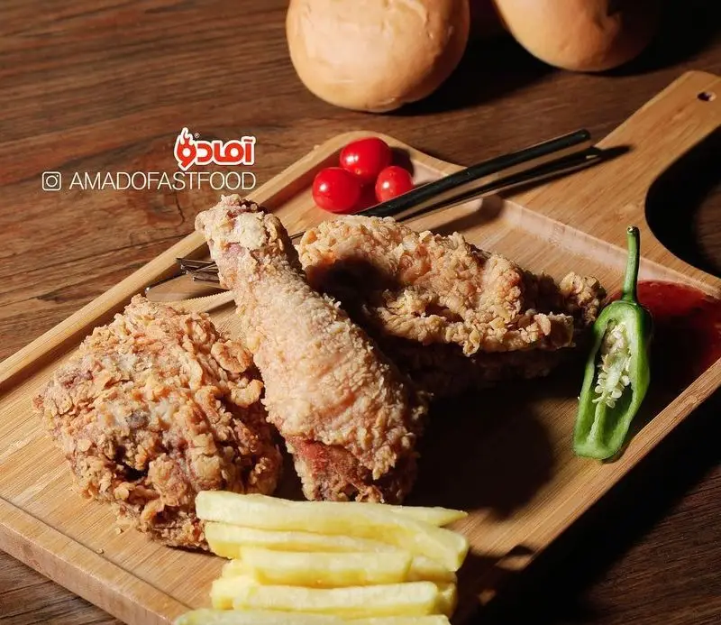 مرغ سوخاری ترد و خوشمزه به همراه سیب‌زمینی سرخ‌کرده، سس، فلفل و گوجه روی تخته چوبی در فست فود پیلوت. غذای محبوب.