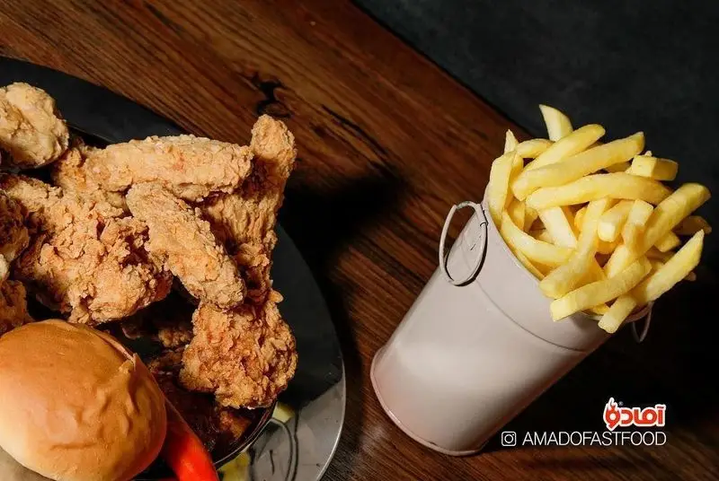 یک وعده غذایی لذیذ از فست فود پیلوت: مرغ سوخاری طلایی و ترد، سیب زمینی سرخ کرده داغ در سطل، و نان تازه.