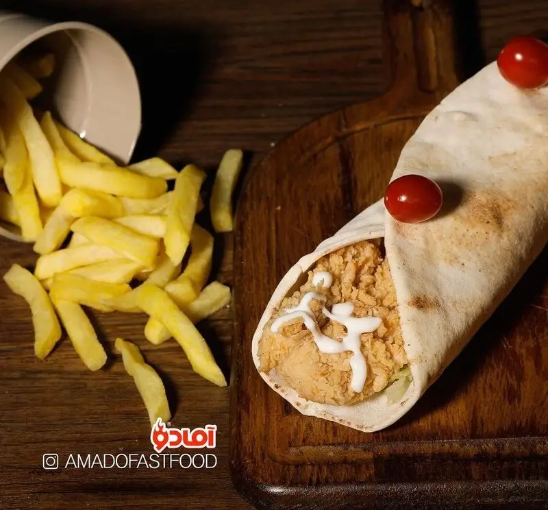 تصویری جذاب از ساندویچ رپ مرغ سوخاری فست فود پیلوت با نان تازه، سس مخصوص، سیب زمینی سرخ کرده و گوجه گیلاسی. خوشمزه و لذیذ.