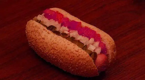 هات داگ خوشمزه رستوران گامبی با نان کنجدی، پیاز، خیارشور و گوجه. غذای فست فود ایده‌آل برای یک وعده سریع و لذیذ.