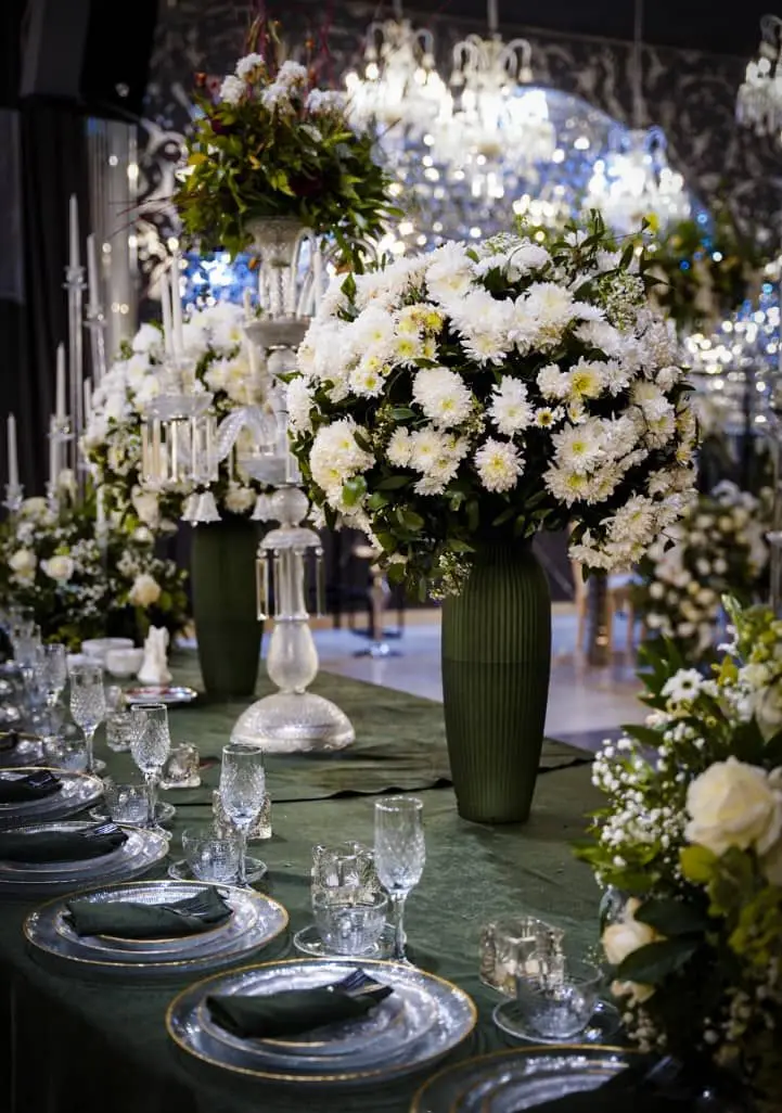 چیدمان لوکس و مجلل میز مراسم با ظروف کرایه بلادی: شامل گلدان، شمعدان، بشقاب و لیوان کریستال برای رویدادهای خاص.