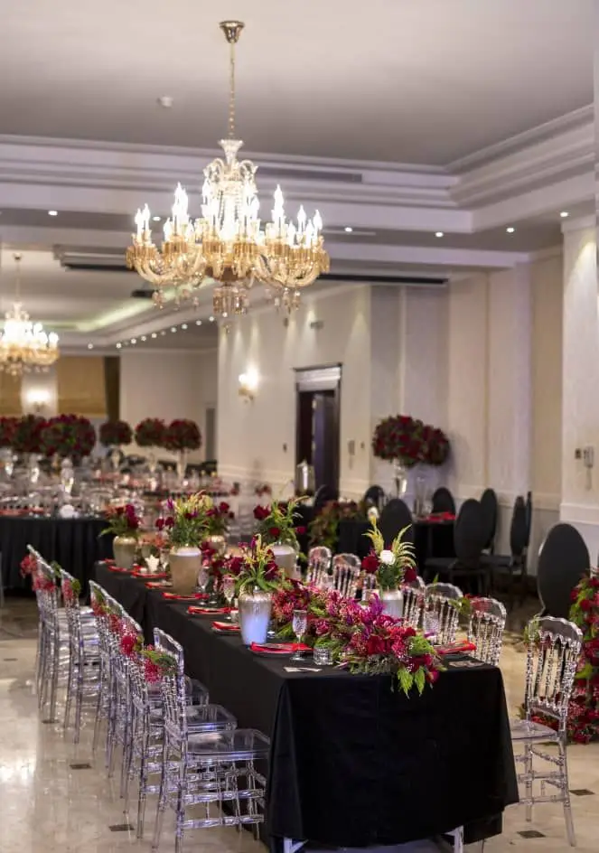 تزیینات و اجاره ظروف شیک برای مراسم جشن و عروسی توسط ظروف کرایه بلادی. میزهای مشکی، صندلی‌های شفاف و گل آرایی قرمز باشکوه.