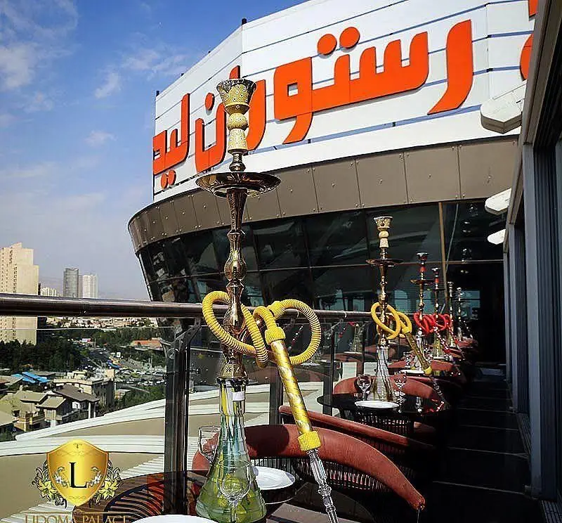 تراس دلنشین فضای باز کاخ رستوران لیدوما با قلیان های آماده، منظره زیبای شهر و آسمان آبی، تجربه ای خاص در رستوران لوکس