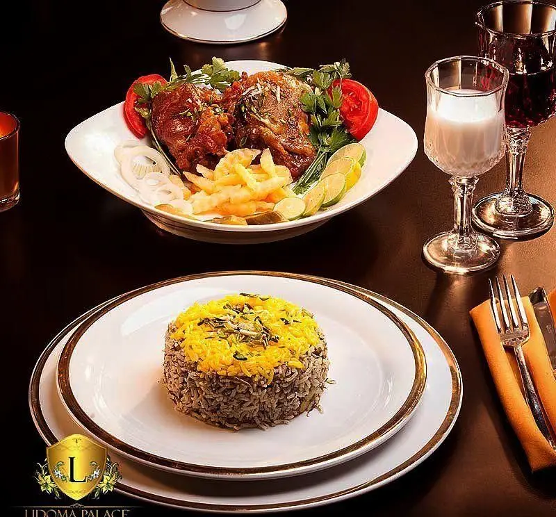 نمای مجلل از غذای ایرانی کاخ رستوران لیدوما شامل مرغ یا گوشت مجلسی، برنج قالبی زعفرانی و مخلفات در محیطی لوکس و شیک.