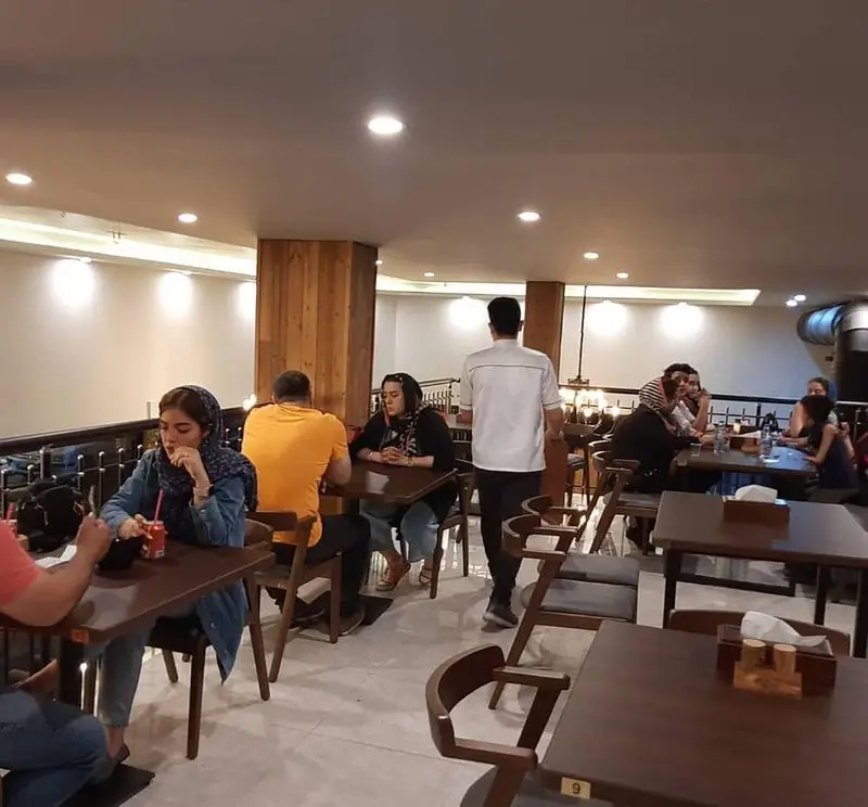 نمایی از فضای داخلی رستوران و کافه پیتزا دکتر آرین (اورجینال فود) با مشتریان نشسته بر سر میزها در محیطی آرام و دلنشین.