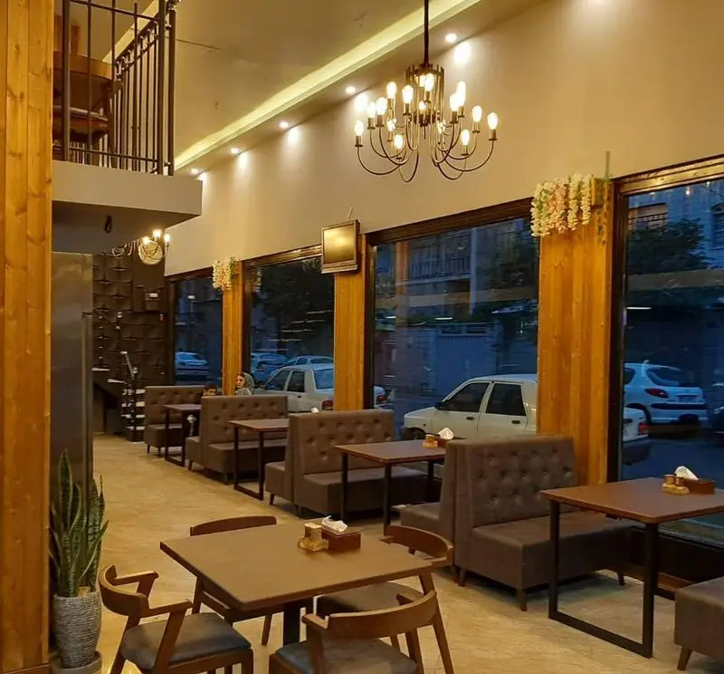 محیط دنج و زیبای رستوران پیتزا دکتر آرین (اورجینال فود) با طراحی مدرن، مبلمان راحت، لوستر شیک و نمایی از شهر از پنجره‌های بزرگ.