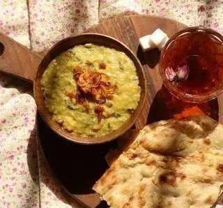 آش مشتی شیرازی، غذایی گرم و سنتی شیرازی با نان تازه و چای، سرو شده در رستوران آش مشتی شیرازی، تجربه طعم اصیل.