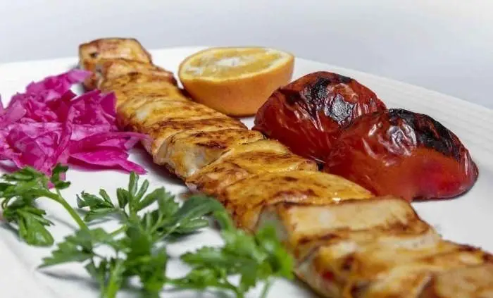 کباب ماهی لذیذ از تهیه غذا حامد فود، با تکه‌های خوشرنگ گوجه کبابی، نارنج تازه، کلم قرمز و سبزی معطر. انتخابی عالی برای شام.