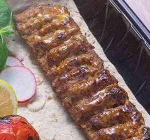 کباب کوبیده لذیذ و آبدار تهیه غذا حامد فود، سرو شده روی نان لواش با گوجه کبابی، لیمو و سبزی تازه. تجربه طعم غذای اصیل ایرانی.